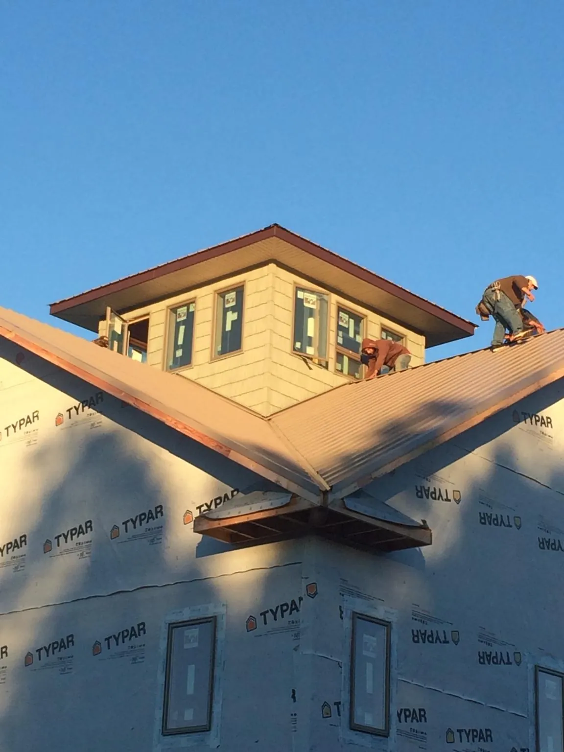 Roofers working around a rooftop cupola on a new metal roof at sunset — Roof Waterproofing in Marysville by Roofing Brothers